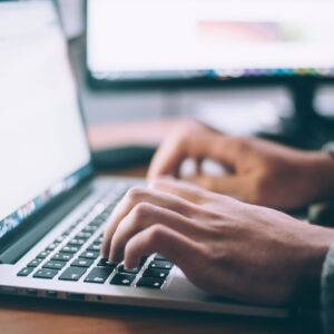 a pair of busy hand is typing on the laptop at the office hours